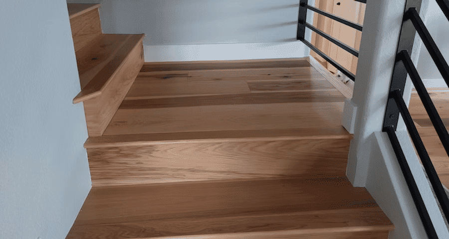Wooden staircase with sleek railing, highlighting natural oak flooring and modern design.