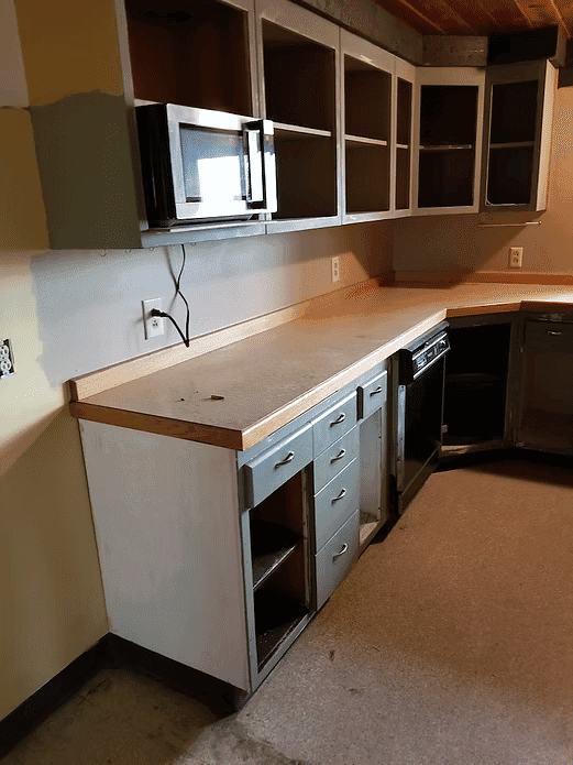 Modern kitchen with gray cabinets, microwave, and countertop in natural light.