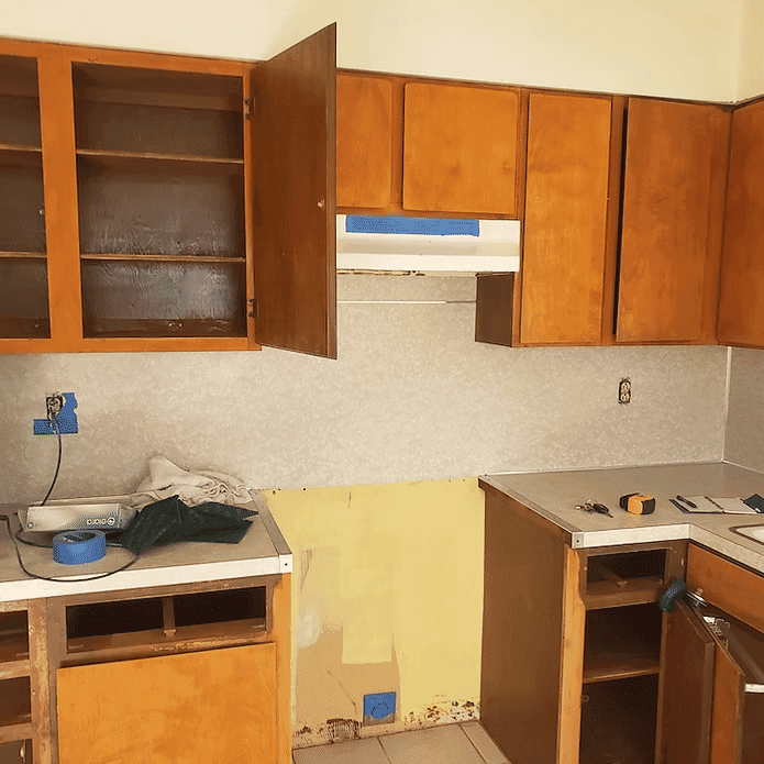 Renovated kitchen with wooden cabinets, countertop, and unfinished wall paint.