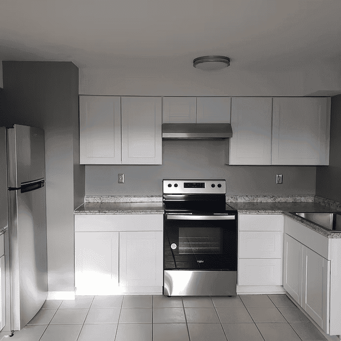 Modern kitchen with white cabinets, stainless steel appliances, and gray walls. Bright and spacious design.