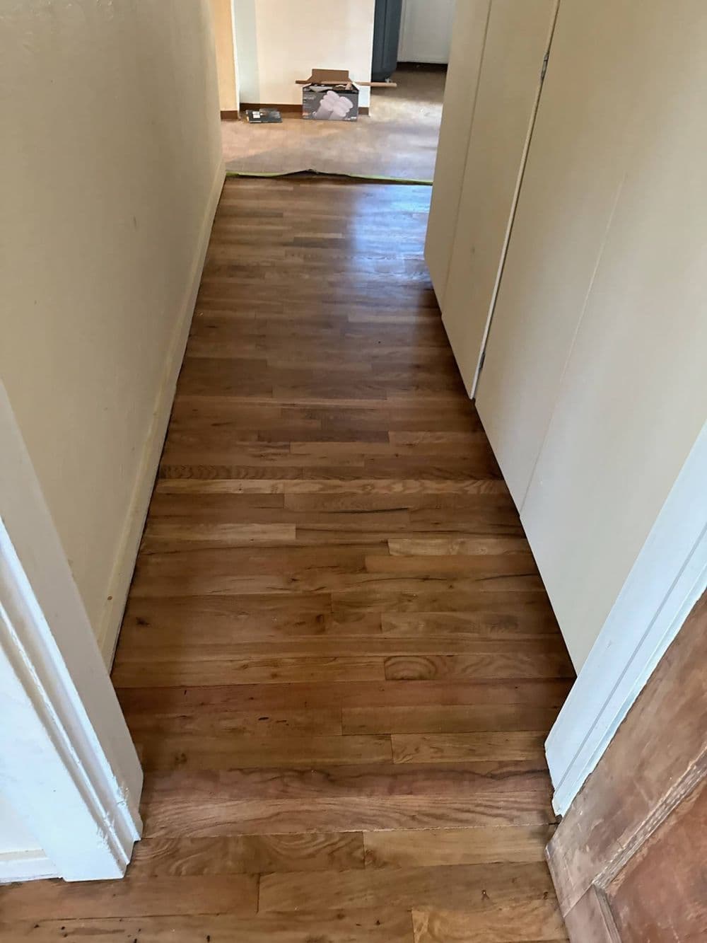 Hallway with polished hardwood floors and open doors leading to adjoining rooms.