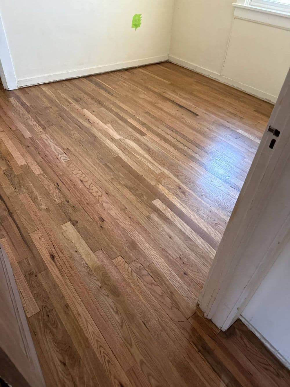 Freshly installed hardwood flooring in a bright, empty room with natural light.