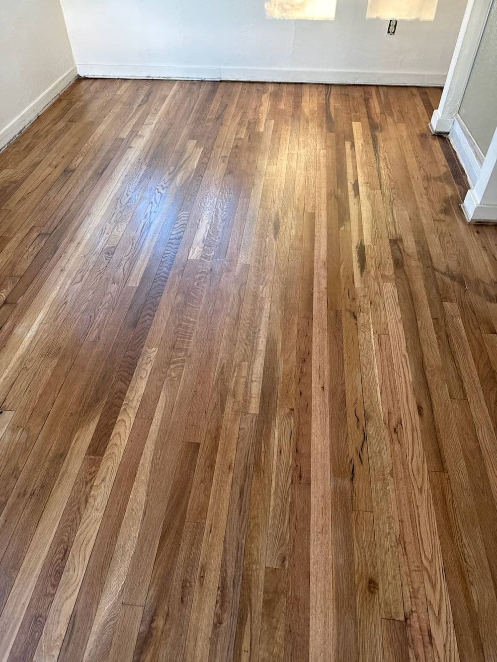 Newly installed hardwood floor with natural wood grain and shine in a bright room.