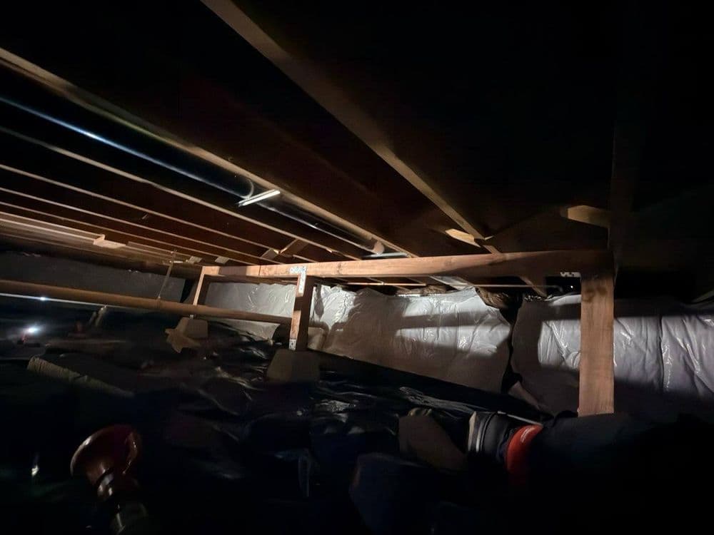 View of a dimly lit attic showing wooden beams and insulation materials.