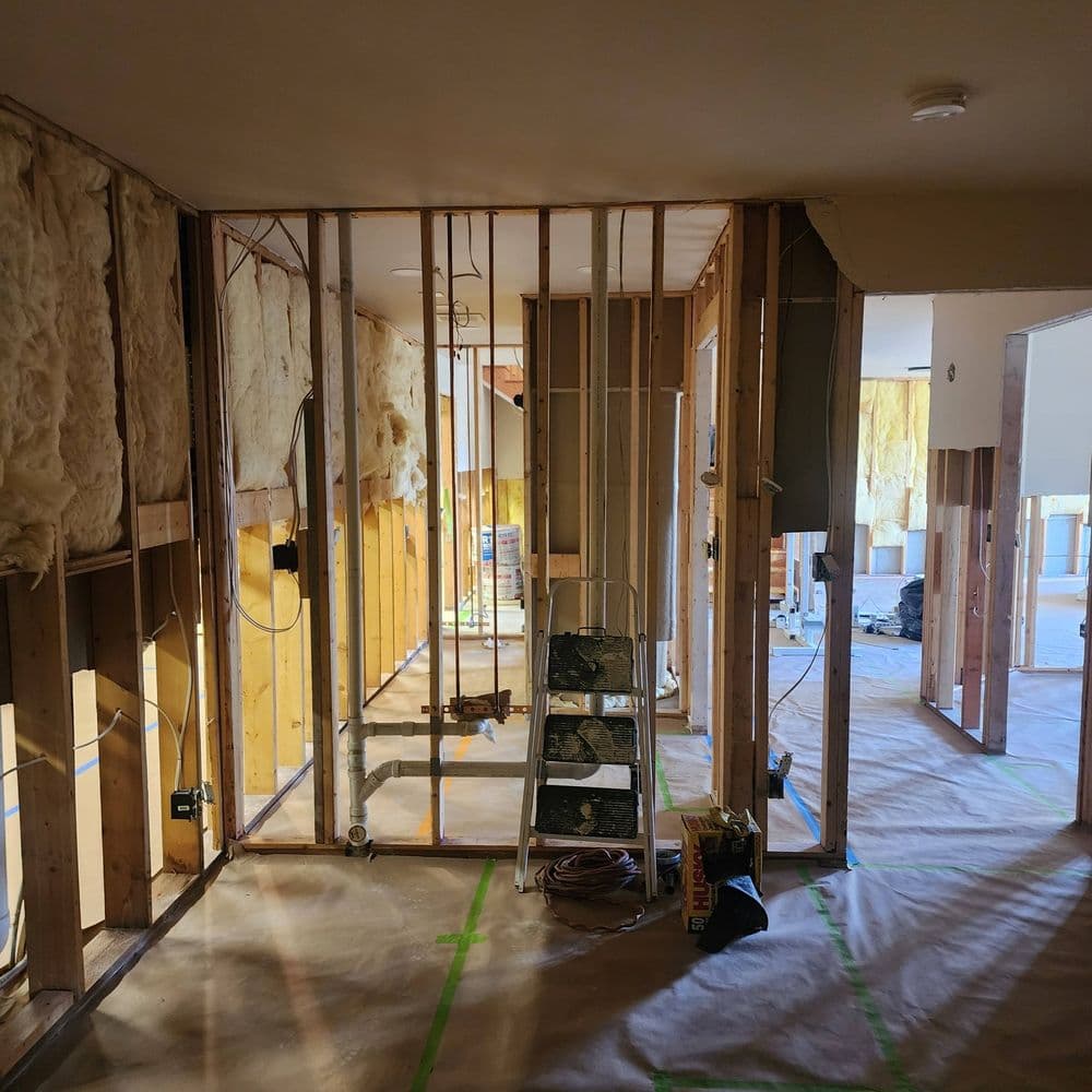 Interior view of a home renovation, showcasing framed walls and construction tools.